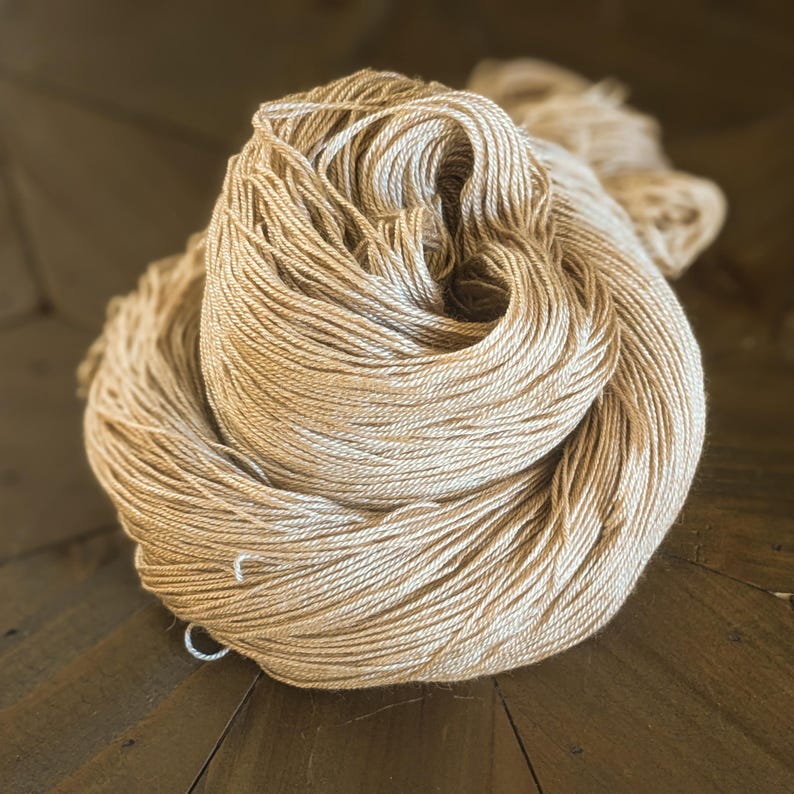 May include: A skein of beige yarn, made from natural fibres, is loosely wound and ready for knitting or crocheting.