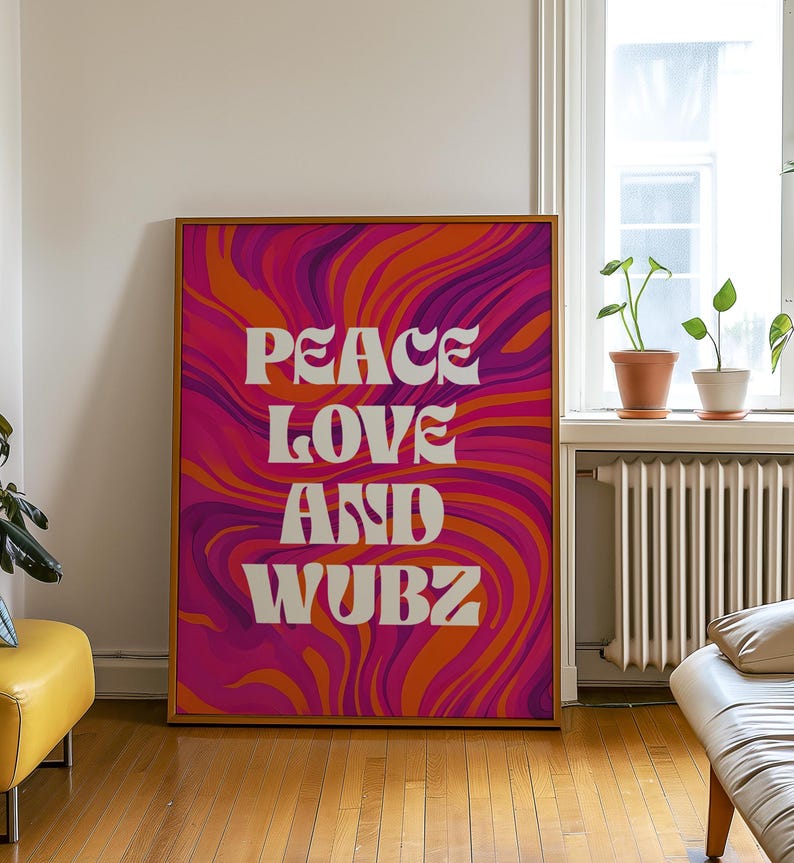 May include: A framed art print with the words "PEACE LOVE AND WUBZ" in white, set against a vibrant, swirling background of orange, pink, and purple. The artwork is displayed in a room with natural light.