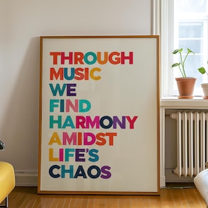 Pu&ograve; includere: Un poster incorniciato con il testo "THROUGH MUSIC WE FIND HARMONY AMIDST LIFE'S CHAOS" in lettere colorate su uno sfondo bianco.