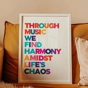 Pu&ograve; includere: Una stampa incorniciata bianca con il testo "THROUGH MUSIC WE FIND HARMONY AMIDST LIFE'S CHAOS" in lettere colorate.