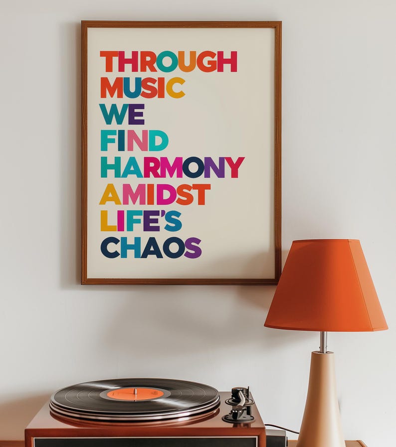 Pu&ograve; includere: Una stampa incorniciata con il testo "THROUGH MUSIC WE FIND HARMONY AMIDST LIFE'S CHAOS" in lettere colorate. La stampa &egrave; appesa a un muro bianco sopra un giradischi e una lampada.