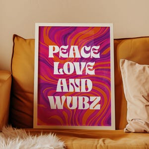 May include: Framed art print with the words "PEACE LOVE AND WUBZ" in white, set against a vibrant background of swirling pink, orange, and purple colors. The artwork is displayed on a yellow couch with pillows.