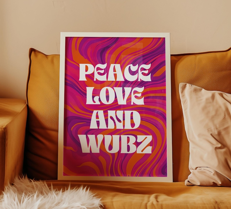 May include: Framed art print with the words "PEACE LOVE AND WUBZ" in white, set against a vibrant background of swirling pink, orange, and purple colors. The artwork is displayed on a yellow couch with pillows.