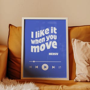 Peut inclure: Une impression encadr&eacute;e bleue avec du texte blanc qui dit "J'aime &ccedil;a quand tu bouges" et le nom de l'artiste "MERSIV" en dessous. L'impression a un bouton de lecture blanc et d'autres commandes de lecteur de musique.