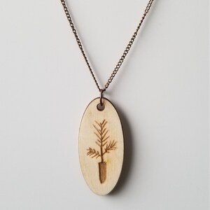 May include: A wooden necklace with a small oval pendant featuring a wood-burned image of a potted tree.
