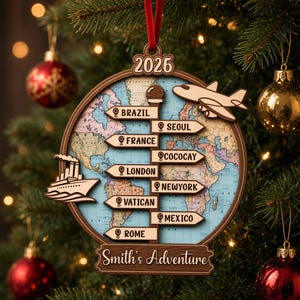 May include: A round wooden Christmas ornament featuring a world map background, a central signpost with locations including Brazil, Seoul, France, Cococay, London, New York, Vatican, and Rome, a wooden airplane, a cruise ship, and the text 2026 and Smith's Adventure.