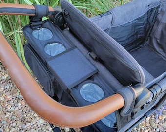 May include: A grey stroller with a brown leather handle and a black storage compartment with cup holders. The stroller has a zipped top and a mesh pocket.