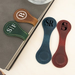 May include: Four leather magnetic bookmarks with personalized initials and names. The bookmarks are in brown, green, blue, and red.