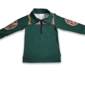 May include: A dark green long-sleeved shirt with a zippered collar and camouflage fabric on the shoulders and upper arms.