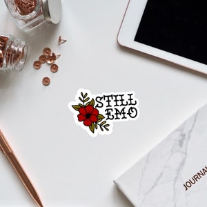 May include: A sticker with a red flower and green leaves with the text "STILL EMO" in black.