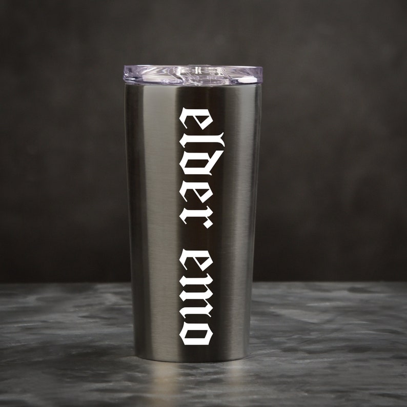 May include: A stainless steel tumbler with a black lid and the words "elder emo" printed in white on the side.