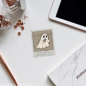 May include: A white ghost holding a blue forget-me-not flower with the text "Forget me not, Forgive me please." on a vintage-style Polaroid photo.