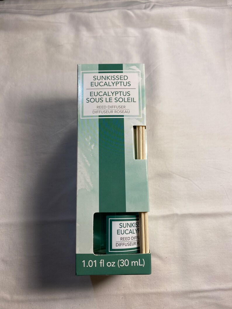 以下が含まれることがあります： 緑と白の箱の中にリードディフューザーが入っています。箱には「Sunkissed Eucalyptus」と「Eucalyptus Sous Le Soleil」の文字が書かれています。ディフューザーは30ml（1.01 fl oz）です。