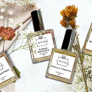 May include: Four glass bottles of perfume with black caps and white labels. The labels have the word "AROME" in black lettering and the names of the scents: "Sweet Saffron", "Citrus Bergamia", "Vanilla Tobacco", and "Bitter Almond".