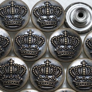 May include: A set of 12 antique gold-toned metal buttons with a crown design. The buttons are round and have a raised design.