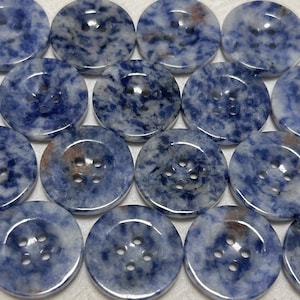 May include: A collection of round buttons with a marbled blue and white pattern. Each button has four holes for sewing. The buttons are made of a stone-like material and have a glossy finish. The buttons are arranged in neat rows.