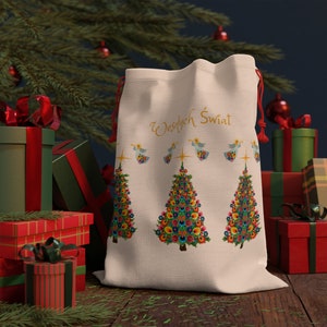 May include: A white fabric gift bag with a drawstring closure. The bag features a festive design with three colorful Christmas trees and the text "Wesołych Świąt" in gold lettering.