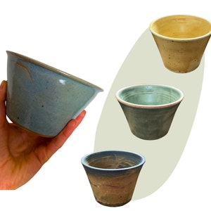 Op de afbeelding: Drie keramische kommen in verschillende kleuren en glazuren. De kommen zijn allemaal rond en hebben een lichte rand. De kom links is lichtblauw met een gespikkelde glazuur. De kom in het midden is lichtgroen met een gespikkelde glazuur. De kom rechts is lichtgeel met een gespikkelde glazuur.