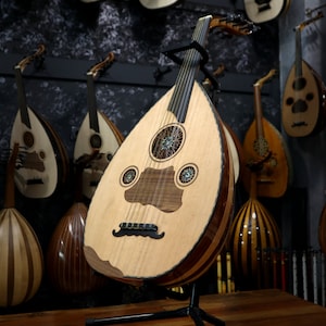 May include: A white ceramic mug with a black handle and the text "But First, Coffee" in a bold, black font. The mug is set against a blurred background, suggesting a cosy setting.