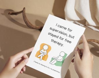 May include: A white greeting card with the text "I came for supervision, but stayed for free therapy." Two cartoon figures are seated in armchairs. The card is held by hands.