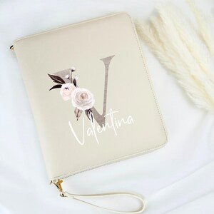 May include: A beige zippered pouch with a floral design and the letter "V" in a brown font. The name "Valentina" is written in white script below the letter.