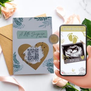 Könnte beinhalten: Eine Schwangerschaftsankündigungskarte mit dem Text "A Little Surprise for You" und einem QR-Code. Ein Smartphone zeigt ein Ultraschallbild mit dem Datum 19.07.2026. Die Karte hat ein goldenes Herzdesign und florale Akzente.