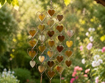 May include: A hanging wind chime featuring a vertical arrangement of interconnected copper-colored wire hearts. Each heart frame contains a flat, reflective, heart-shaped metal insert. Three small brass bells hang from the bottom of the structure.
