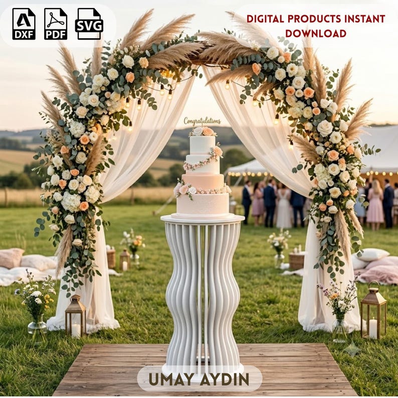 May include: A white, multi-tiered wedding cake with floral accents sits on a white, vertically slatted, hourglass-shaped pedestal. Behind it is a large, arched floral display featuring pampas grass, white and peach roses, and sheer white fabric.