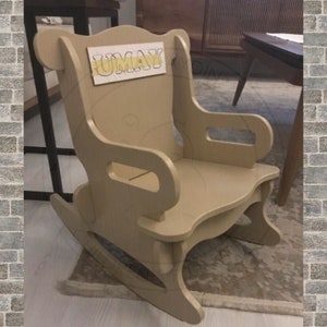 May include: A light brown wooden rocking chair with a cutout design. The chair has a high back and armrests. The name "UMAY" is written on the back of the chair in yellow letters.