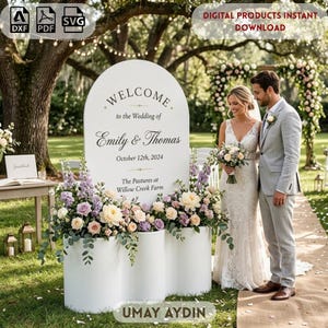 May include: A white arched wedding welcome sign featuring the text Welcome to the Wedding of Emily & Thomas October 12th, 2024 The Pastures at Willow Creek Farm, decorated with a floral arrangement of light pink, cream, and purple flowers.