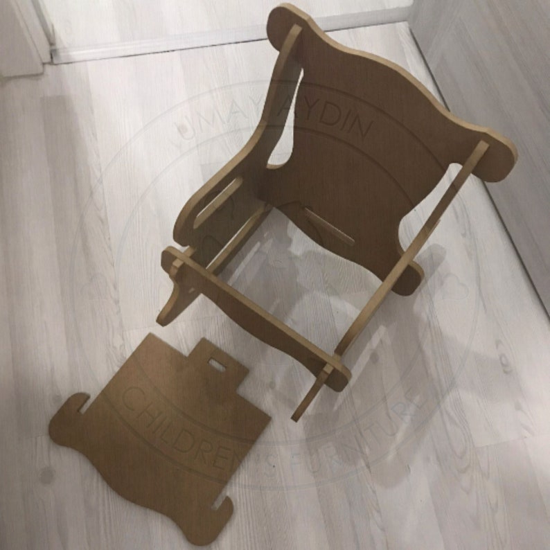 May include: A disassembled wooden chair for children. The chair is made of light brown wood and has a simple design. The chair is in two pieces, the seat and the back.
