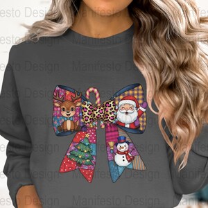 Op de afbeelding: Donkergrijze sweatshirt met een kleurrijk kerststrikontwerp. De strik bevat een rendier, de kerstman, een sneeuwpop en een kerstboom. De strik heeft een luipaardprint zuurstok in het midden. Het ontwerp is een patchwork-stijl.