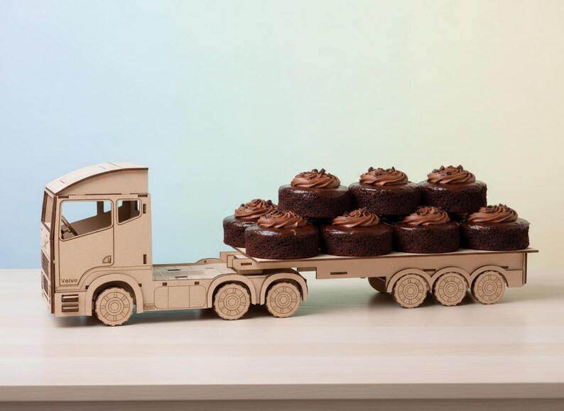 May include: A wooden toy lorry transporting chocolate cupcakes with chocolate frosting. The cupcakes are stacked on the flatbed. The lorry is constructed from light-coloured wood and has detailed features.