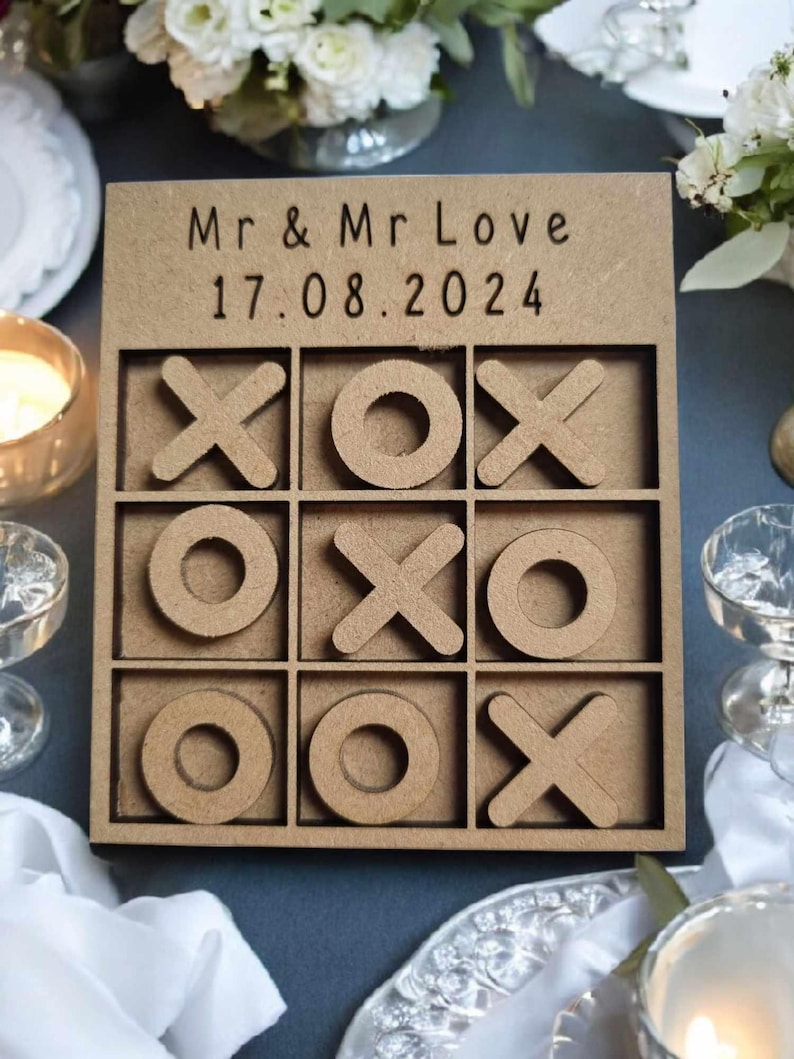 May include: A wooden tic-tac-toe game with the text "Mr & Mr Love 17.08.2024" on the top. The game is made of light brown wood and has a natural finish.