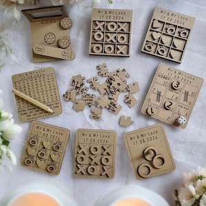 May include: A set of wooden wedding games for guests to play at a reception. The games include tic-tac-toe, a word search, a puzzle, and a ring toss. The games are all personalized with the couple's names and wedding date.