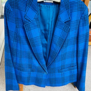 May include: A blue blazer with a black plaid pattern. The blazer has a single button closure and two pockets.