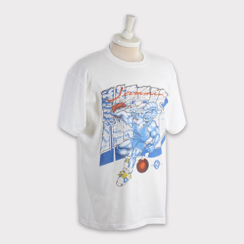 May include: White t-shirt featuring a cartoon ram in a basketball uniform, holding a basketball. The graphic is in blue, red, and yellow. The word "Jammin" is printed above the ram in red.