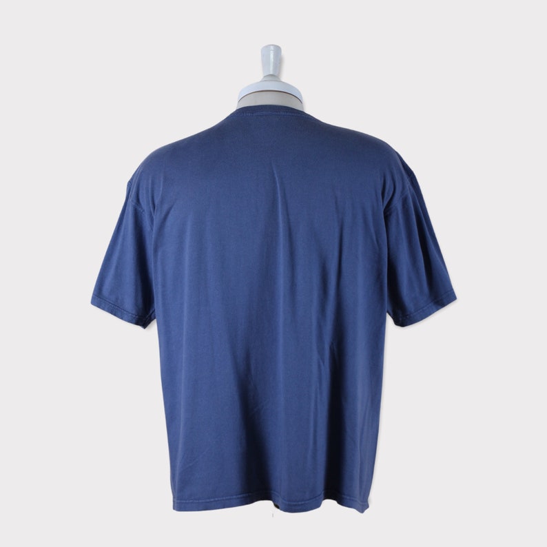 Puede incluir: Una camiseta lisa de color azul oscuro con mangas cortas. La camiseta est&aacute; en un maniqu&iacute;.