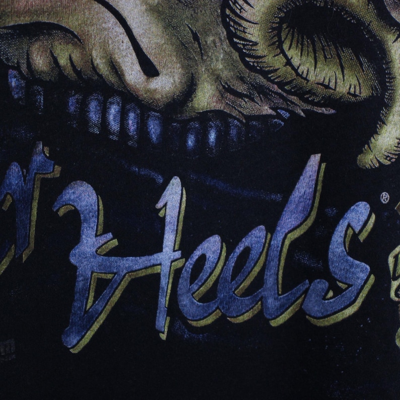 May include: Black t-shirt featuring a skull graphic and the text "Boot Heel's" in a blue and gold font.
