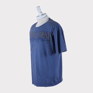 Puede incluir: Una camiseta azul con un estampado gr&aacute;fico descolorido de "Grateful Dead" en una fuente estilizada. El texto "Your Face" est&aacute; impreso debajo del nombre de la banda.