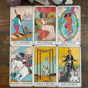May include: A set of ten tarot cards featuring colorful illustrations of people and symbols. The cards are arranged in two rows of five. The cards include "Six of Swords", "The Empress", "The World", "Knight of Swords", "Four of Wands", and "The Chariot".