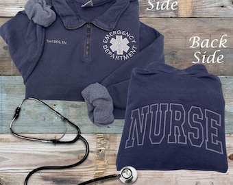 May include: A navy blue sweatshirt with a zipper. The front of the sweatshirt has an embroidered white star of life with the words "Emergency Department". The back of the sweatshirt has the word "NURSE" embroidered in white.