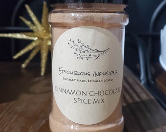 Könnte beinhalten: Ein Glasgefäß mit braunem Deckel, gefüllt mit einer braunen Gewürzmischung. Das Etikett ist braun mit weißem Text, der "Epicurious Infusions Locally Made. Locally Loved. Cinnamon Chocolate Spice Mix" lautet.