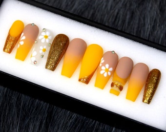 May include: Set of ten yellow and gold ombre press-on nails with white daisy flower accents.