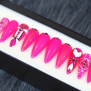 Puede incluir: Conjunto de diez u&ntilde;as postizas stiletto rosas con dise&ntilde;os geom&eacute;tricos y pedrer&iacute;a.
