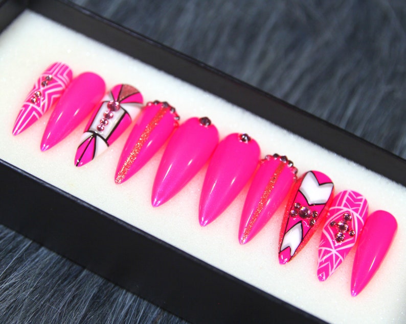 Puede incluir: Conjunto de diez u&ntilde;as postizas stiletto rosas con dise&ntilde;os geom&eacute;tricos y pedrer&iacute;a.