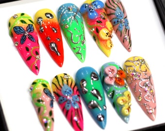 May include: A set of ten colorful, hand-painted fake nails with floral and butterfly designs. The nails are long and pointed, with a variety of colors including pink, blue, green, yellow, and red.