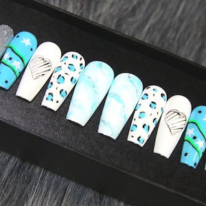 May include: Set of ten false nails with different designs. The designs include blue and white marble, leopard print, blue with white stars and a green stripe, and white with a black heart.