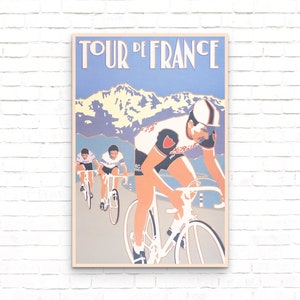 May include: A vintage poster for the Tour de France cycling race. The poster features three cyclists racing up a mountain pass. The poster is in a blue, white, and red color scheme. The text "Tour de France" is printed in a bold, white font at the top of the poster.