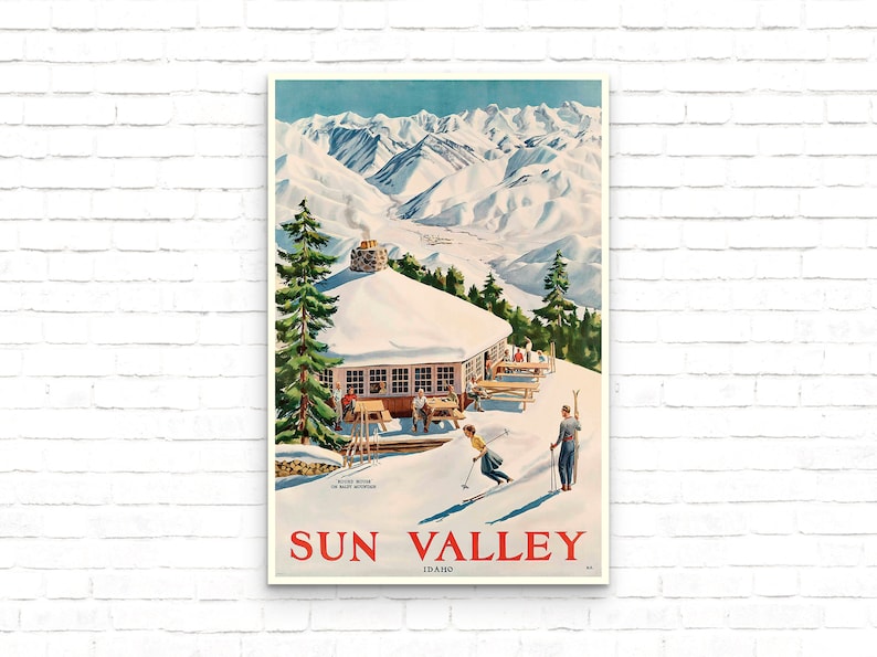 Puede incluir: Un cartel de viaje vintage para Sun Valley, Idaho, que presenta un paisaje monta&ntilde;oso nevado con una caba&ntilde;a de esqu&iacute; y esquiadores. El cartel tiene un cielo azul, nieve blanca y un logotipo rojo y blanco con el texto "Sun Valley, Idaho".